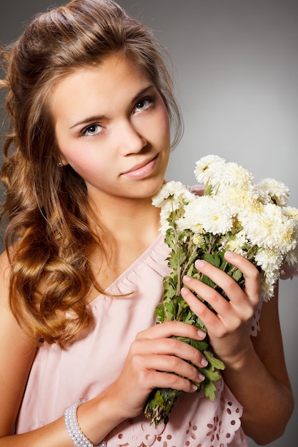 Hermoso retrato de una joven atractiva en un jardín florido Mujer con cabello rizado en un sombrero de paja y vestido blanco Concepto de nueva temporada