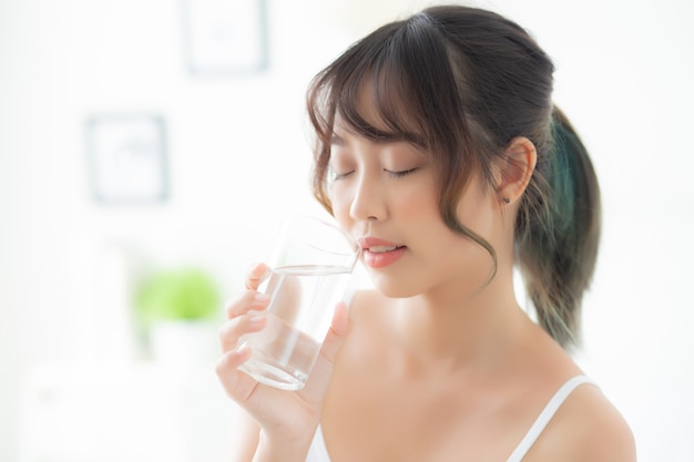 Hermoso retrato joven mujer asiática caucásica sonriendo con nutrición sediento y bebiendo un vaso de agua