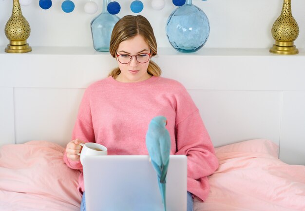 Hermoso retrato mujer joven independiente sentada relajarse y ocio trabajando internet de computadora portátil en línea en la cama en el dormitorio, chica alegre con gesto feliz y éxito, concepto de estilo de vida.