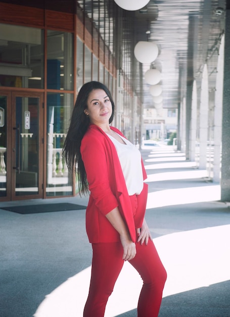 Hermoso retrato de mujer joven morena vestida con traje de pantalón clásico rojo