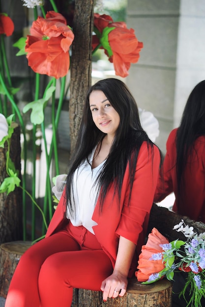 Hermoso retrato de mujer joven morena vestida con traje de pantalón clásico rojo