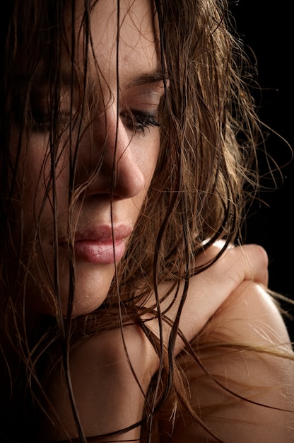 Hermoso retrato de mujer morena de pelo largo, cara mojada, foto de estudio