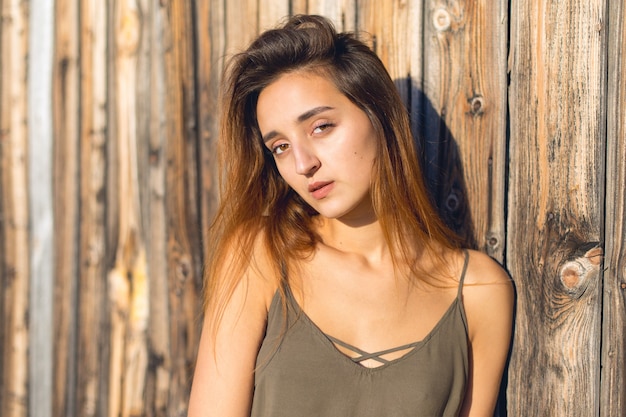 Hermoso retrato de una niña sobre un fondo de madera. Chica con un vestido ligero en los tirantes.