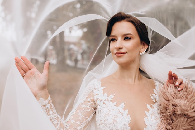 Un hermoso retrato de la novia bajo un velo Mujer elegante con maquillaje y peinado profesional Una foto de las delicadas manos de la novia escondidas bajo un velo Día de la boda Matrimonio Novia de moda