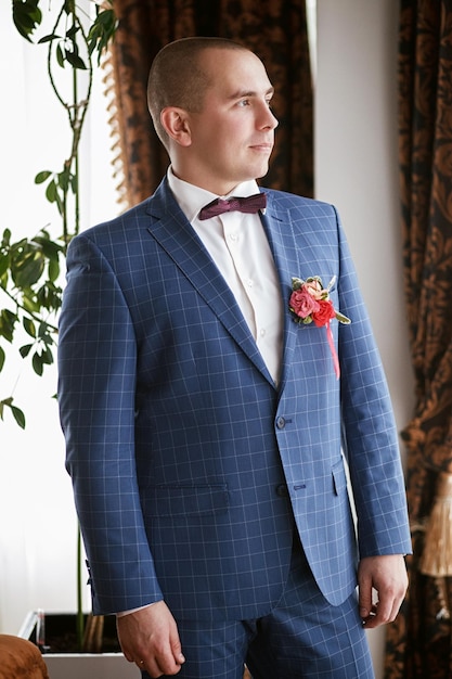 Foto hermoso retrato del novio en un traje de boda que se encuentra en la ventana