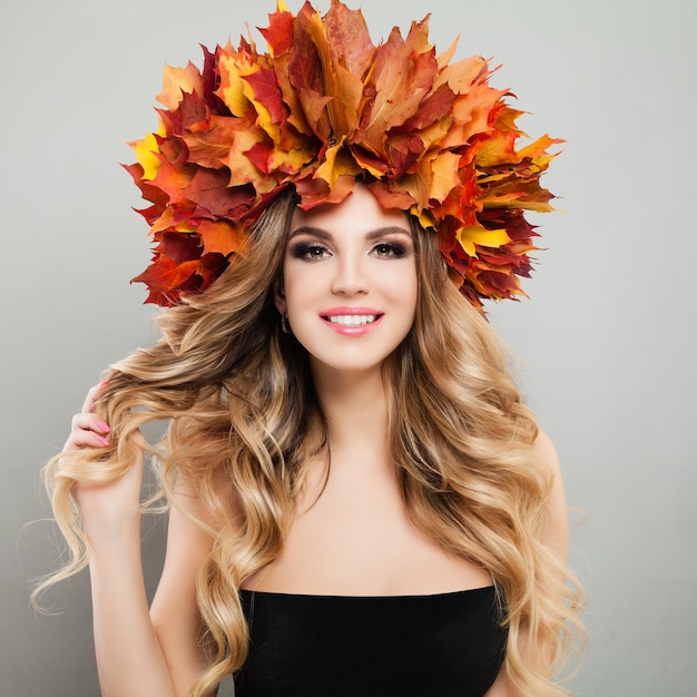 Hermoso retrato otoñal de mujer muy alegre en hojas de otoño corona Maquillaje cabello rubio y rizado