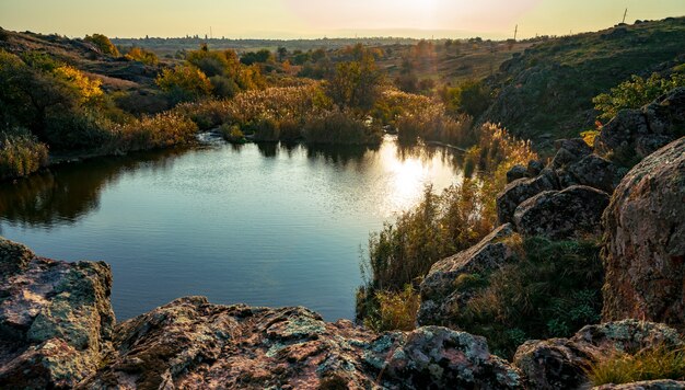 Un hermoso riachuelo reluciente entre grandes piedras blancas y vegetación verde en las colinas