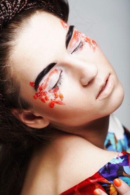 Hermoso rostro femenino joven con maquillaje multicolor de moda brillante