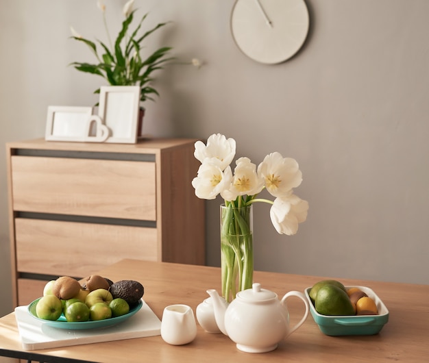 Hermoso servicio de té en mesa de madera. Decoración interior del hogar, ramo de flores en florero, mesa con juego de tetera.