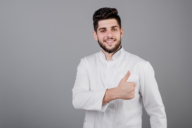 Hermoso sonriente joven médico de Oriente Medio aislado sobre gris