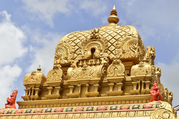 Hermoso templo adornado hindú de oro contra un cielo nublado en un día soleado