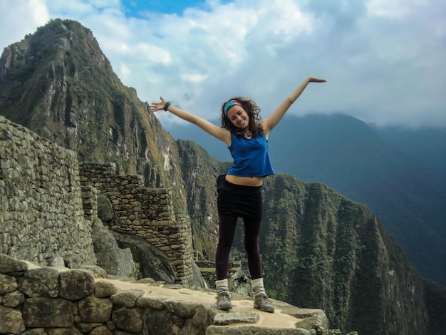 hermoso turista con los brazos abiertos en las ruinas de machu picchu, cusco - peru