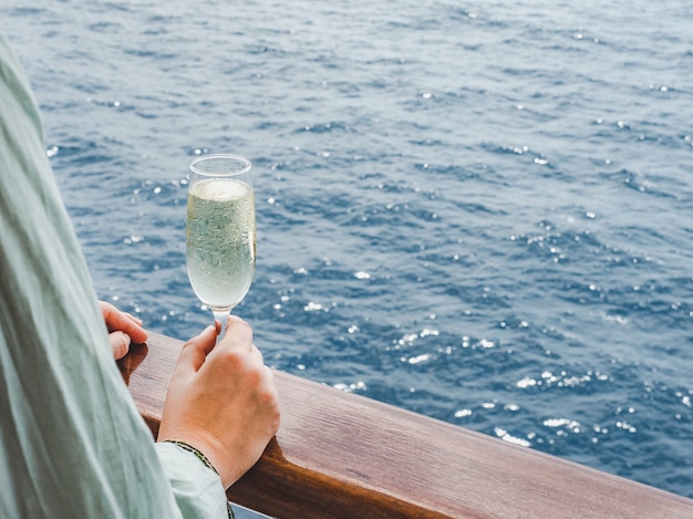 Hermoso vaso con una bebida sobre las olas del mar y los rayos del sol. Vista superior, primer plano. Concepto de ocio y viajes