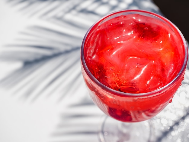 Hermoso vaso con un cóctel rosa y hielo