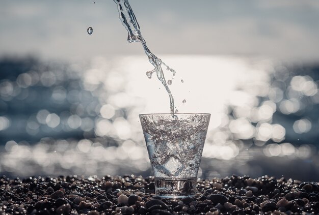 Foto hermoso vaso con hielo y agua mineral pura junto al mar.