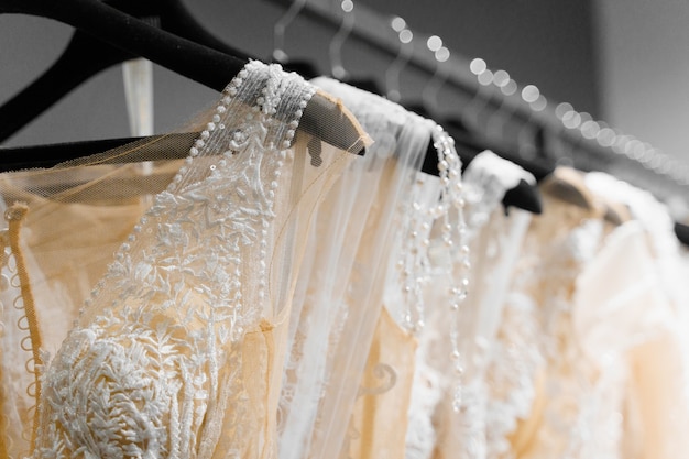 Hermoso vestido de novia blanco crema en perchas en salón de bodas. Colgantes de perlas y cristales en las mangas de un vestido de novia.