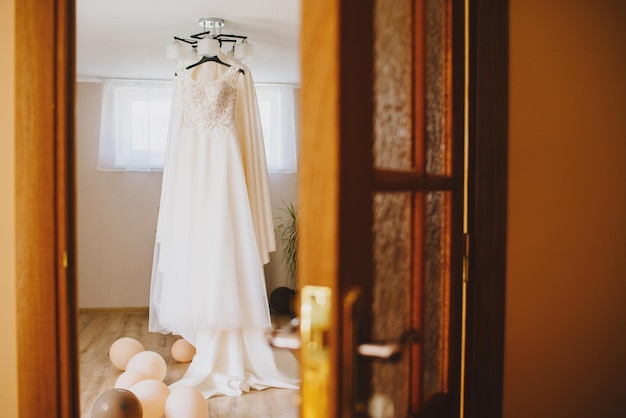 Hermoso vestido de novia colgado en el candelabro de la habitación