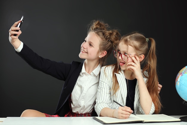 Hermosos amigos divertidos de la escuela haciendo selfie en el pasillo de la escuela por teléfono