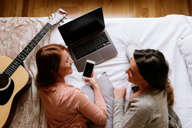 Hermosos amigos usando la computadora portátil en el dormitorio. Concepto de mejor amigo.