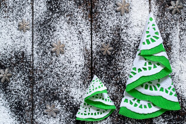 Hermosos árboles de Navidad hechos a mano de servilletas sobre fondo nevado de madera con espacio de copia