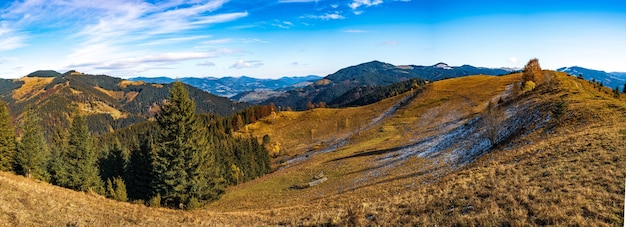 Hermosos bosques coloridos que cubren las montañas de los Cárpatos y un pequeño pueblo con el telón de fondo de un cálido cielo otoñal