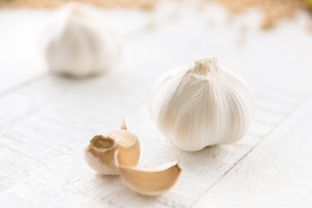 Hermosos bulbos de ajo y algunos dientes en la mesa de madera blanca