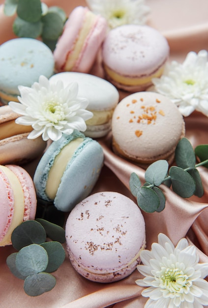 Hermosos coloridos macarrones sabrosos, flores blancas y eucalipto sobre un fondo textil