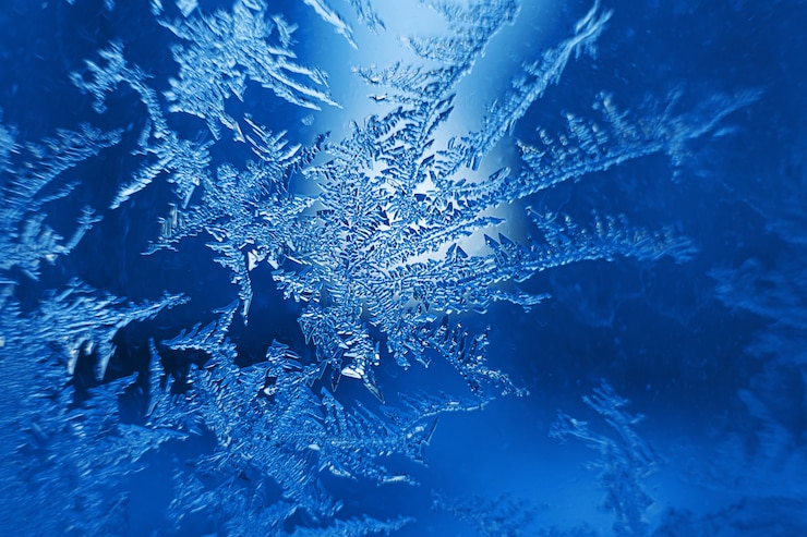 Foto hermosos copos de nieve congelados sobre vidrio, fondo de foto macro, tema de invierno