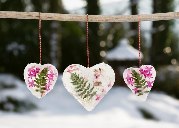 Foto hermosos corazones congelados de árbol hechos de hojas de helecho de hielo y flores de jacinto rosado colgando afuera