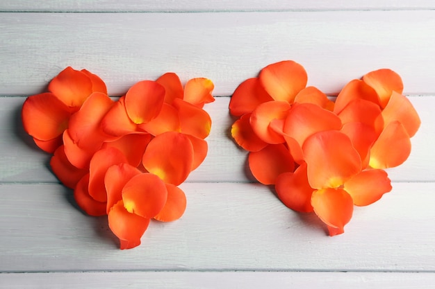 Hermosos corazones de pétalos de rosa sobre fondo de madera