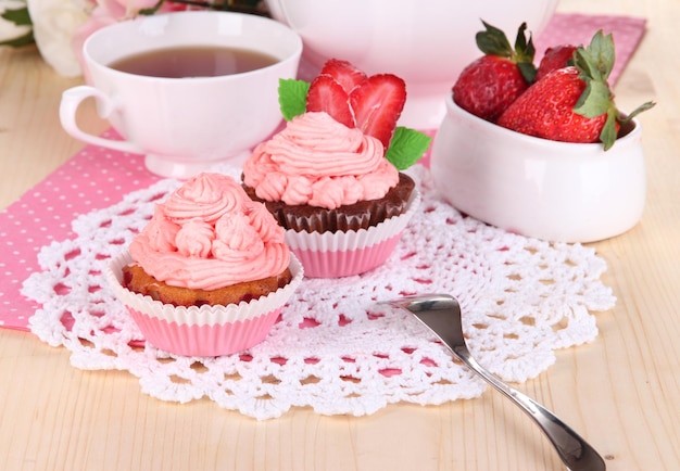 Hermosos cupcakes de fresa y té con sabor en el primer plano de la mesa de comedor