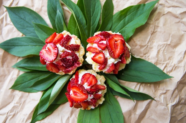 Hermosos y deliciosos cupcakes con fresas en hojas verdes