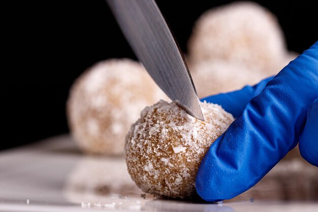 Hermosos dulces con coco se cortan con un cuchillo en un plato blanco sobre un fondo negro