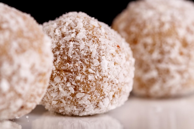 Hermosos dulces con coco en un plato blanco sobre un fondo negro