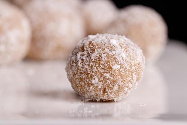 Hermosos dulces con coco en un plato blanco sobre un fondo negro