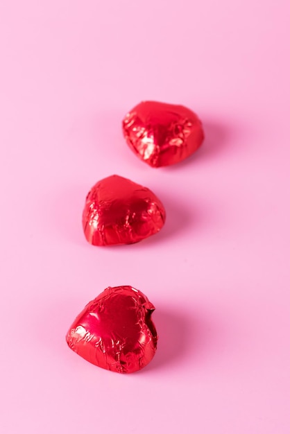 Hermosos dulces de corazones de chocolate rojo sobre fondo rosa Fondo de vacaciones del día de San Valentín