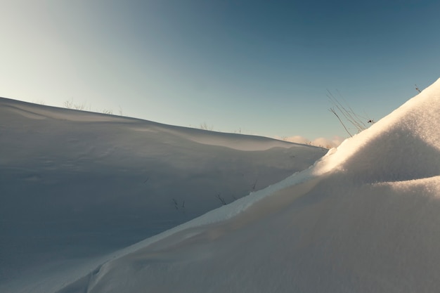 Hermosos fenómenos naturales de la temporada de invierno, suelo cubierto y césped con una gruesa capa de nieve después de un ciclón con tormentas y nevadas, clima frío y helado de invierno y ventisqueros.