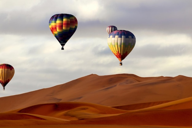 Hermosos globos coloridos de aire caliente y nubes dramáticas sobre las dunas de arena en el desierto de Namib