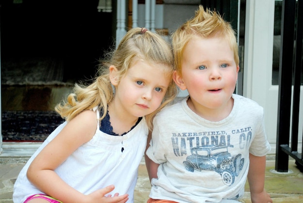 Foto hermosos hermanos mirando lejos sentados en la puerta