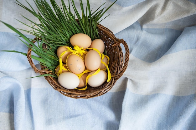 Hermosos huevos de Pascua pintados, un huevo con una cara linda, los huevos yacen en una canasta de madera junto con la hierba verde, postal de Pascua