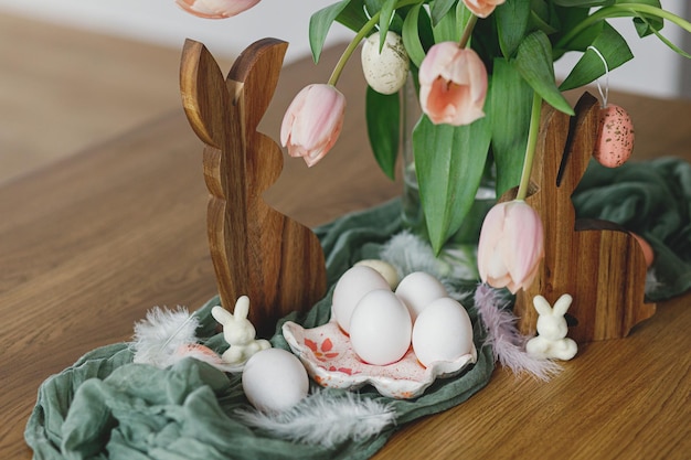 Hermosos huevos de tulipanes y decoración de conejitos en mesa de madera Decoración de Pascua de granja moderna Feliz Pascua Portahuevos hecho a mano con estilo Huevos naturales Ramo de tulipanes rosas y conejitos rústicos