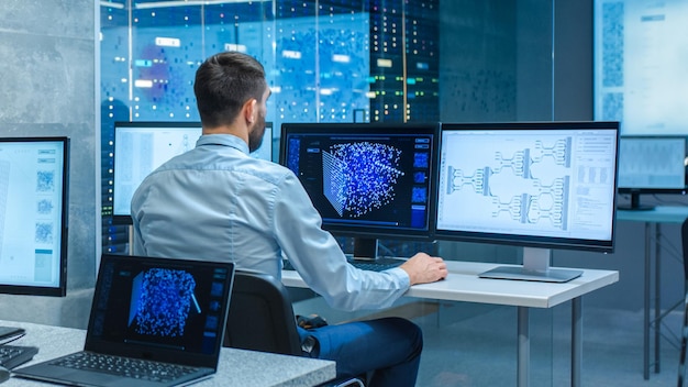 Hermosos ingenieros informáticos y científicos crean una red neuronal en su estación de trabajo La oficina está llena de pantallas que muestran representaciones 3D de redes neuronales