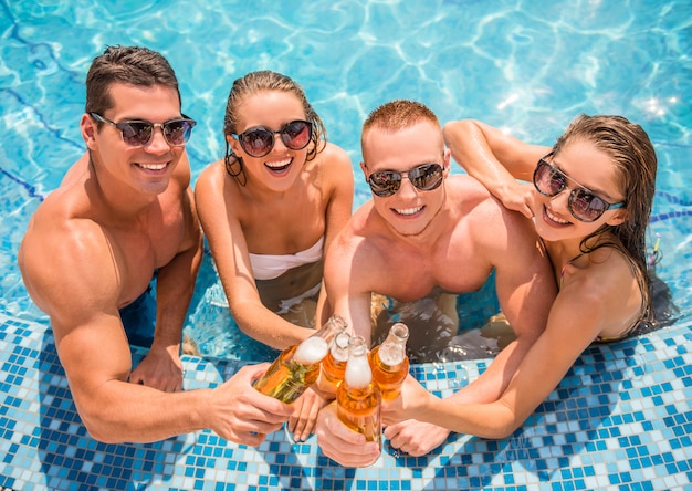 Hermosos jóvenes divirtiéndose en la piscina.