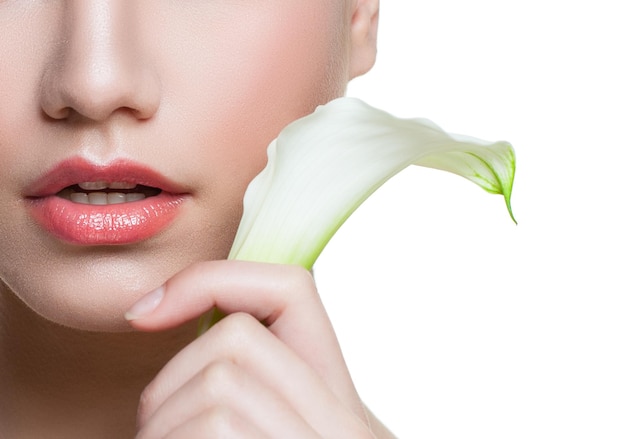 Hermosos labios femeninos con brillo de labios de color natural y flor de cala de lirio blanco aislado