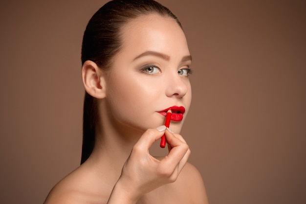 Foto hermosos labios femeninos con maquillaje y pincel en blanco. proceso de trabajo del artista de maquillaje