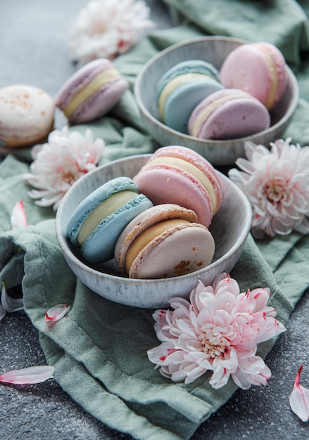 Hermosos macarrones coloridos y sabrosos y flores blancas sobre un fondo de hormigón