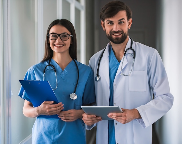 Hermosos médicos jóvenes están mirando a cámara.