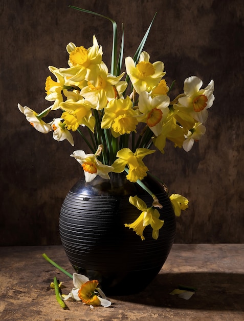 Hermosos narcisos en jarrón negro sobre un fondo de madera