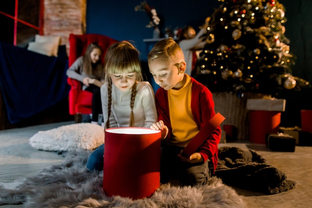 Hermosos niños pequeños miran regalo mágico