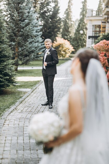 hermosos novios se abrazan en un área grande, detrás de ellos un palacio de color claro